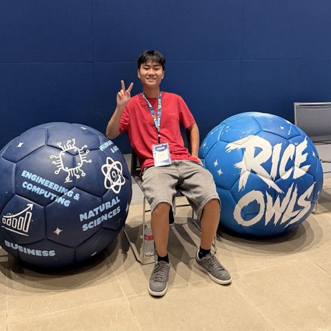 Sitting between two giant Rice soccer balls — one painted with the academic schools, the other reading Rice Owls — wearing a SOAR name badge