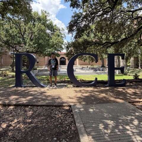 Standing inside the giant RICE letters beneath the live oaks, with the Welcome Center in the background
